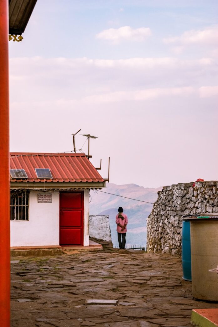 A man standing in front of a building with a red door